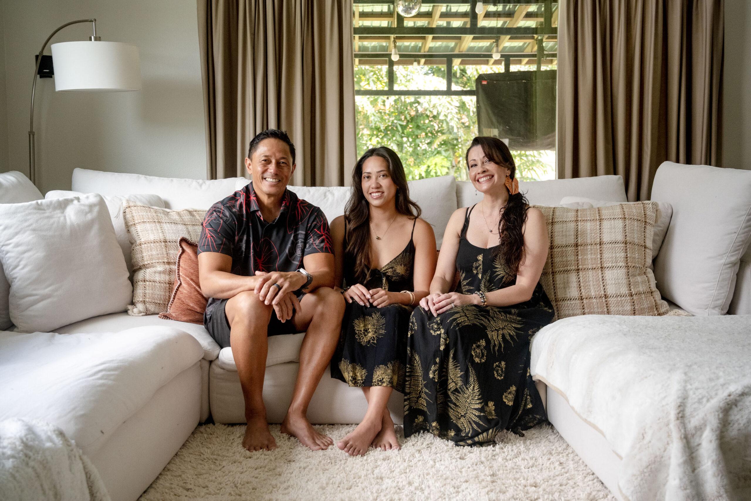 Portrait of Dom, Ashley, and Caron Badis sitting on their couch in Honolulu, Hawaii.