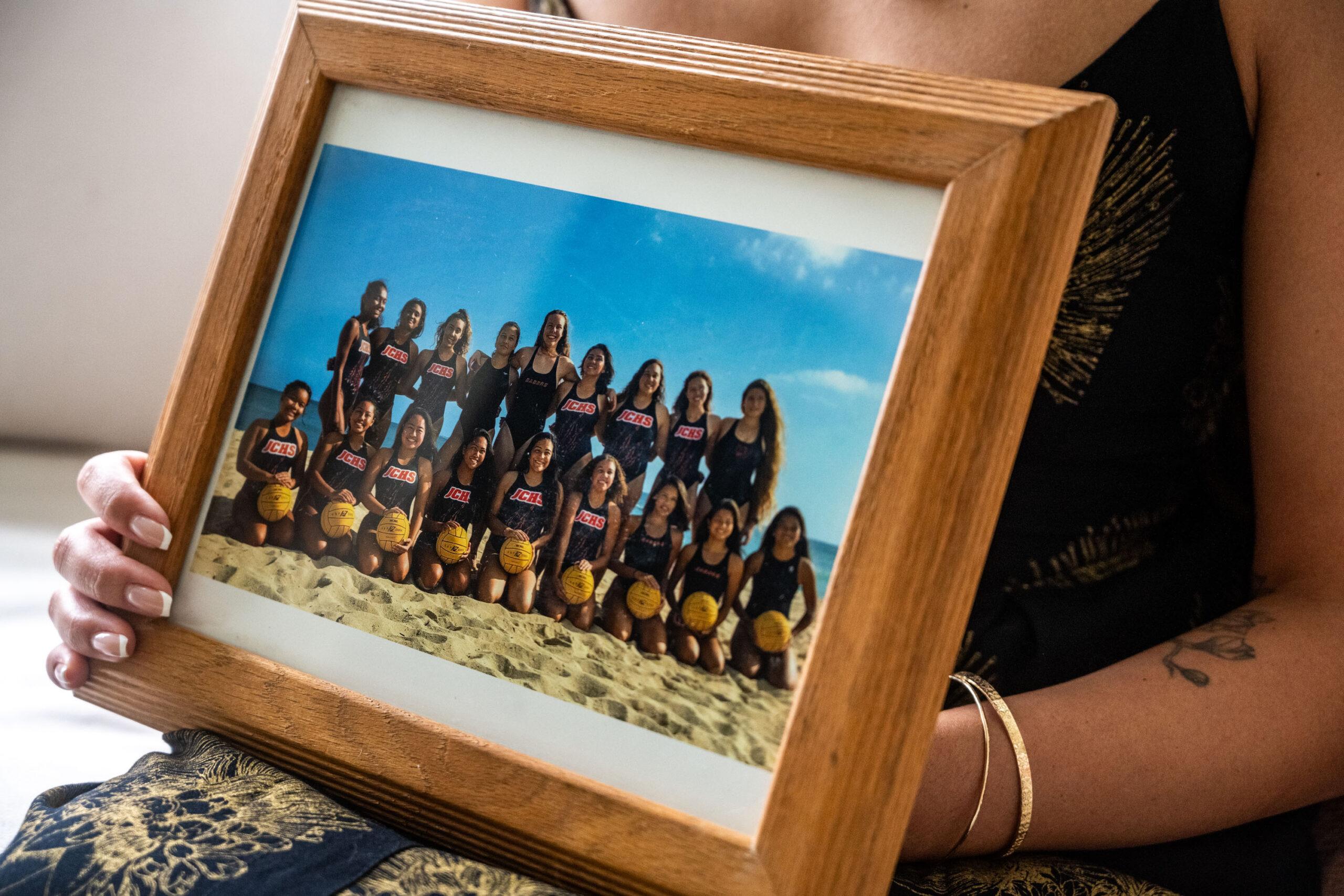 Close up photo of Ashley Badis holding her James Campbell High School girls' water polo team photo.