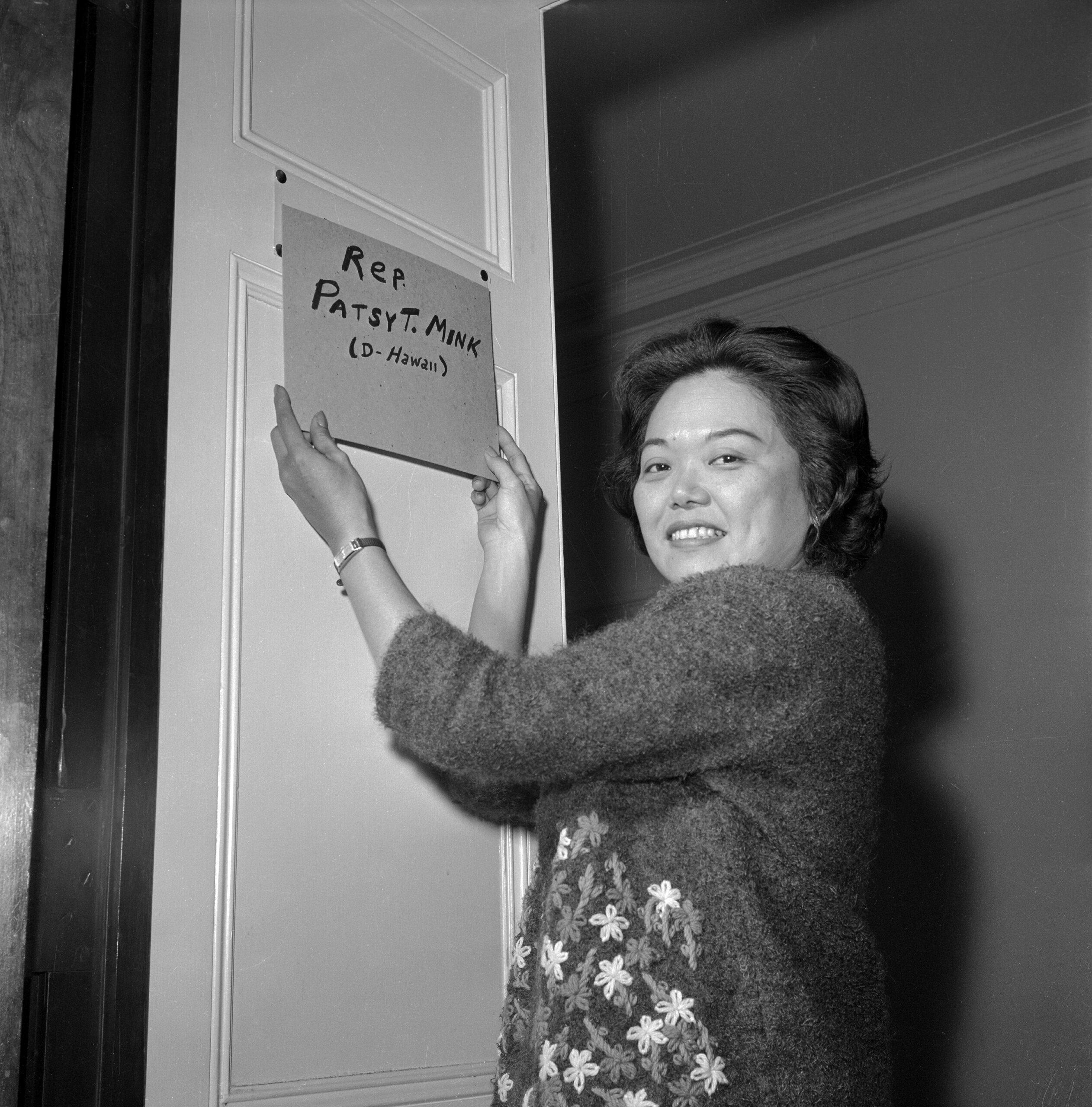 Representative Patsy Takemoto Mink (D-Hawaii) puts a homemade nameplate on the door of her new office in the 89th Congress.