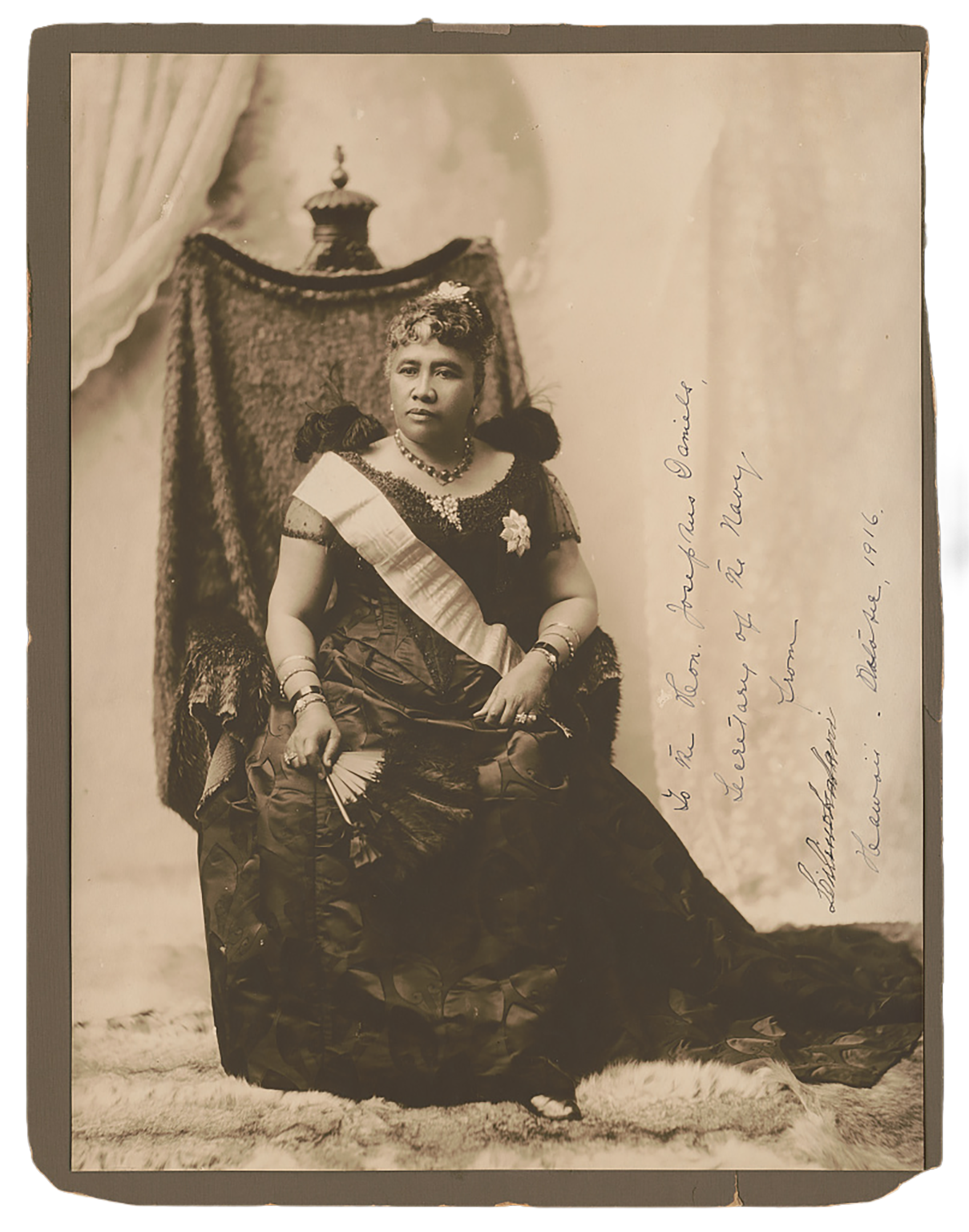 Queen Lili‘uokalani seated on a throne. The writing reads, “To the Hon. Josephus Daniels, Secretary of the Navy, from Liliuokalani, Hawaii, October 1916."